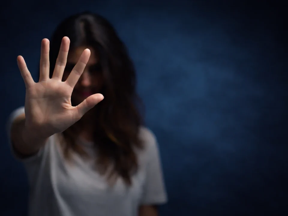 abwehrende Hand einer Frau vor dunklem Hintergrund